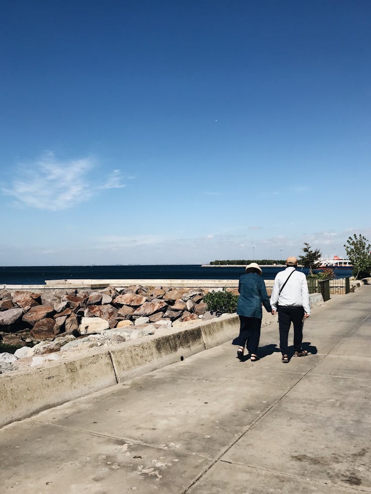 Man And Woman Walking On Road On Sea Shore