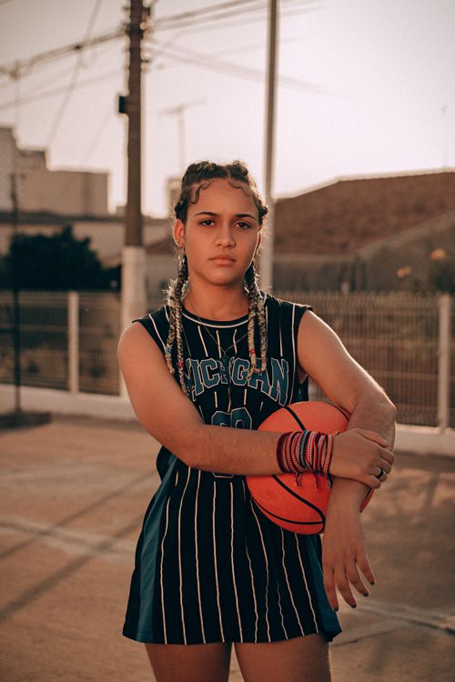 Free Confident young woman with braided hair holding a basketball on an outdoor court. Stock Photo