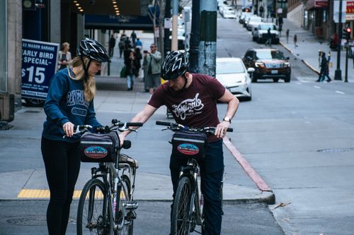 Free Two cyclists pause on a street to plan their route in a busy urban environment. Stock Photo