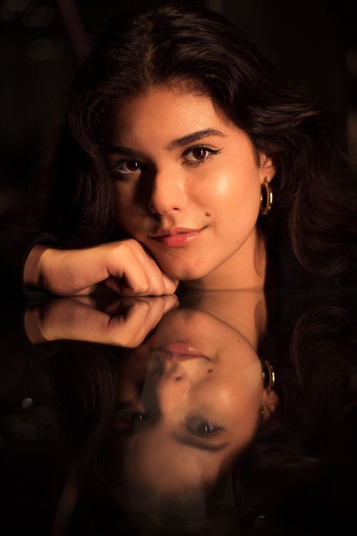 Free A captivating portrait of a woman reflected on a glass surface, showcasing elegance and mystery. Stock Photo