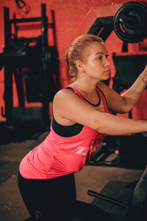 Free Young woman working out in a gym wearing a pink tank top, demonstrating fitness lifestyle. Stock Photo