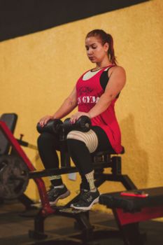 A woman exercising on a leg curl machine in the gym, promoting fitness and a healthy lifestyle.