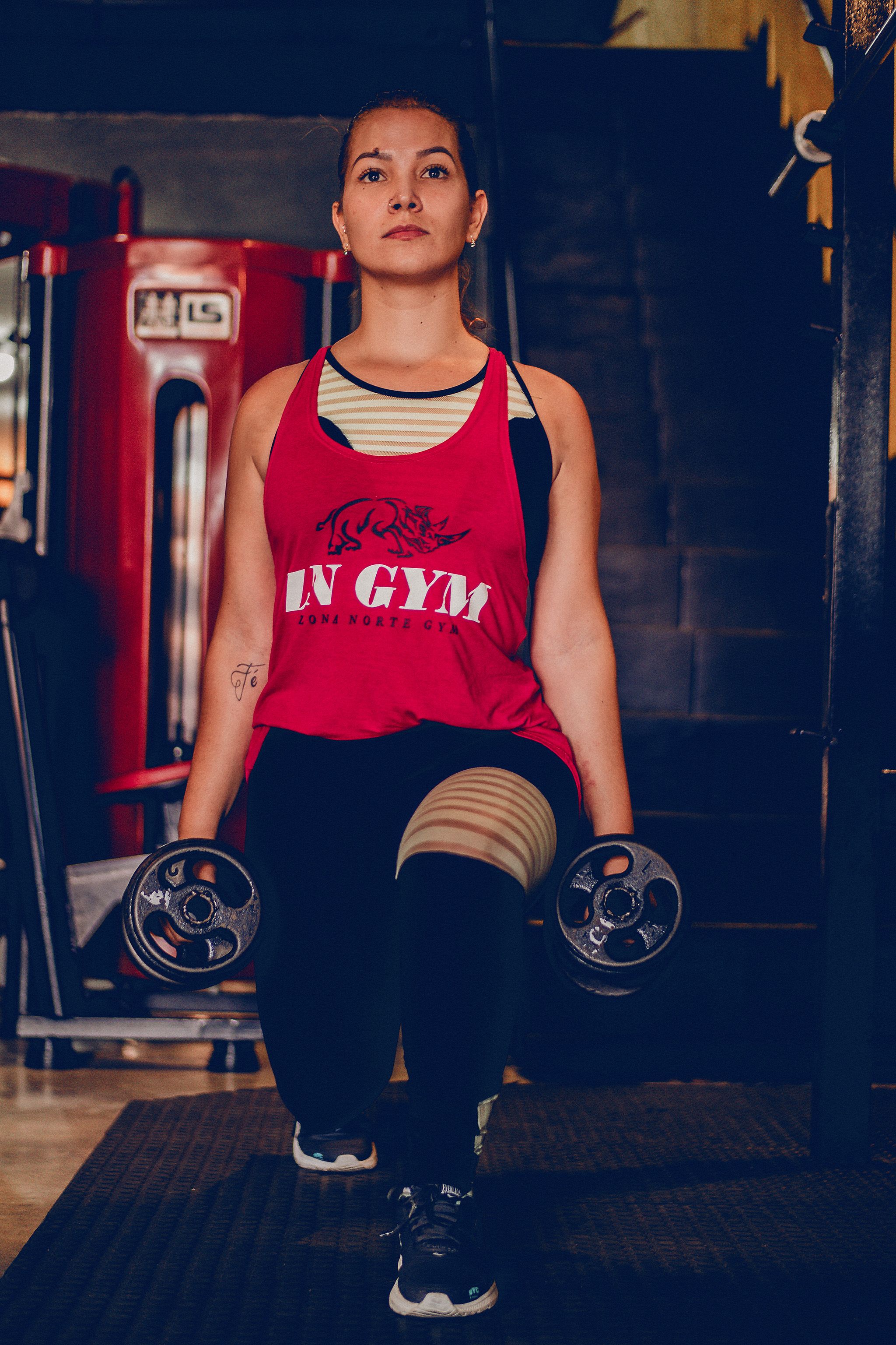 Focused woman performing lunges with dumbbells in a modern gym setting.
