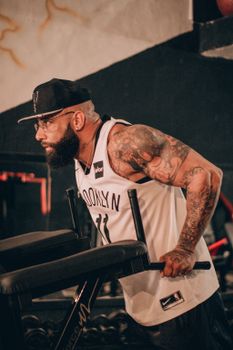 A bearded man with tattoos is exercising indoors, showcasing a healthy lifestyle.