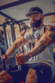 A tattooed, bearded man working out indoors, focused on fitness and health.