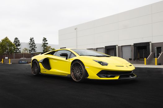 A striking yellow luxury car parked on a modern urban street, showcasing elegance and power.