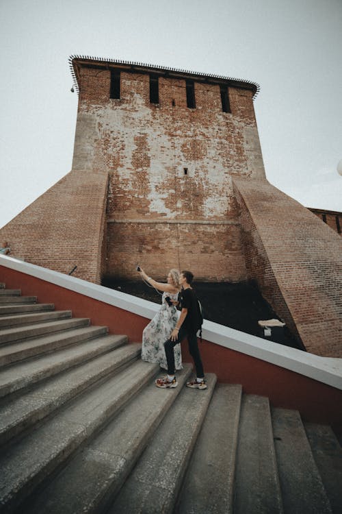 Free Young Couple Making Selfie on Stairs with Old Building as Background Stock Photo