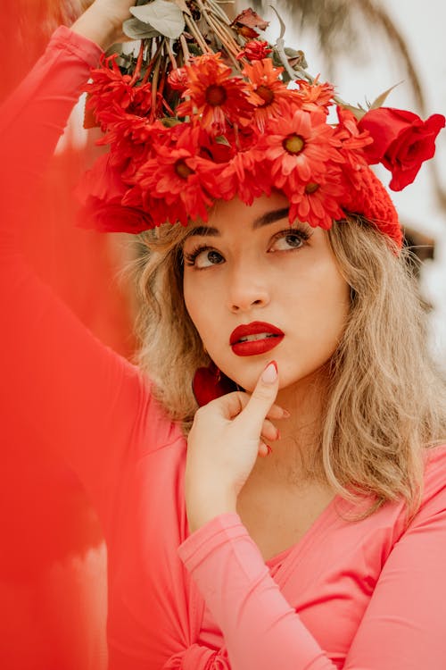 Woman Wearing Red Lipstick and Holding Red Flowers Above Her Head 