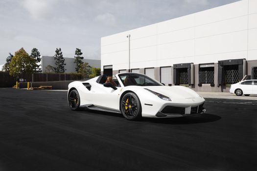 A sleek white sports car parked outdoors in a commercial area, featuring modern design.