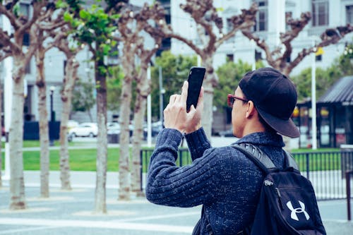 Man Wearing Black Jacket and Holding Black Android Smartphone