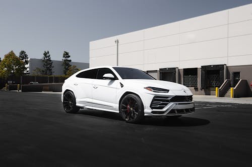 A White Super Car on Asphalt Road Near White Building 