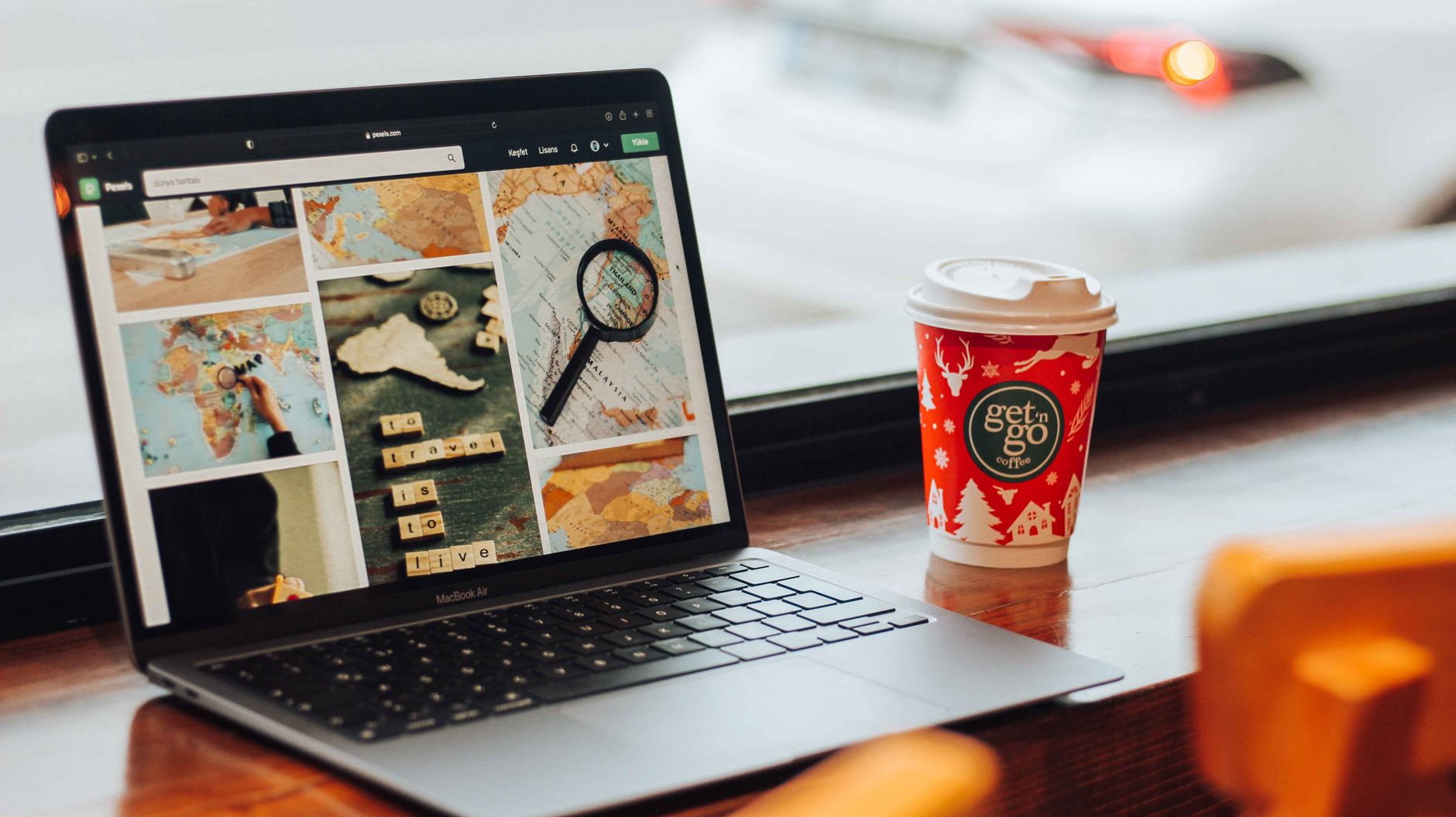 A stylish workspace featuring a laptop displaying travel images and a festive coffee cup on a wooden table.