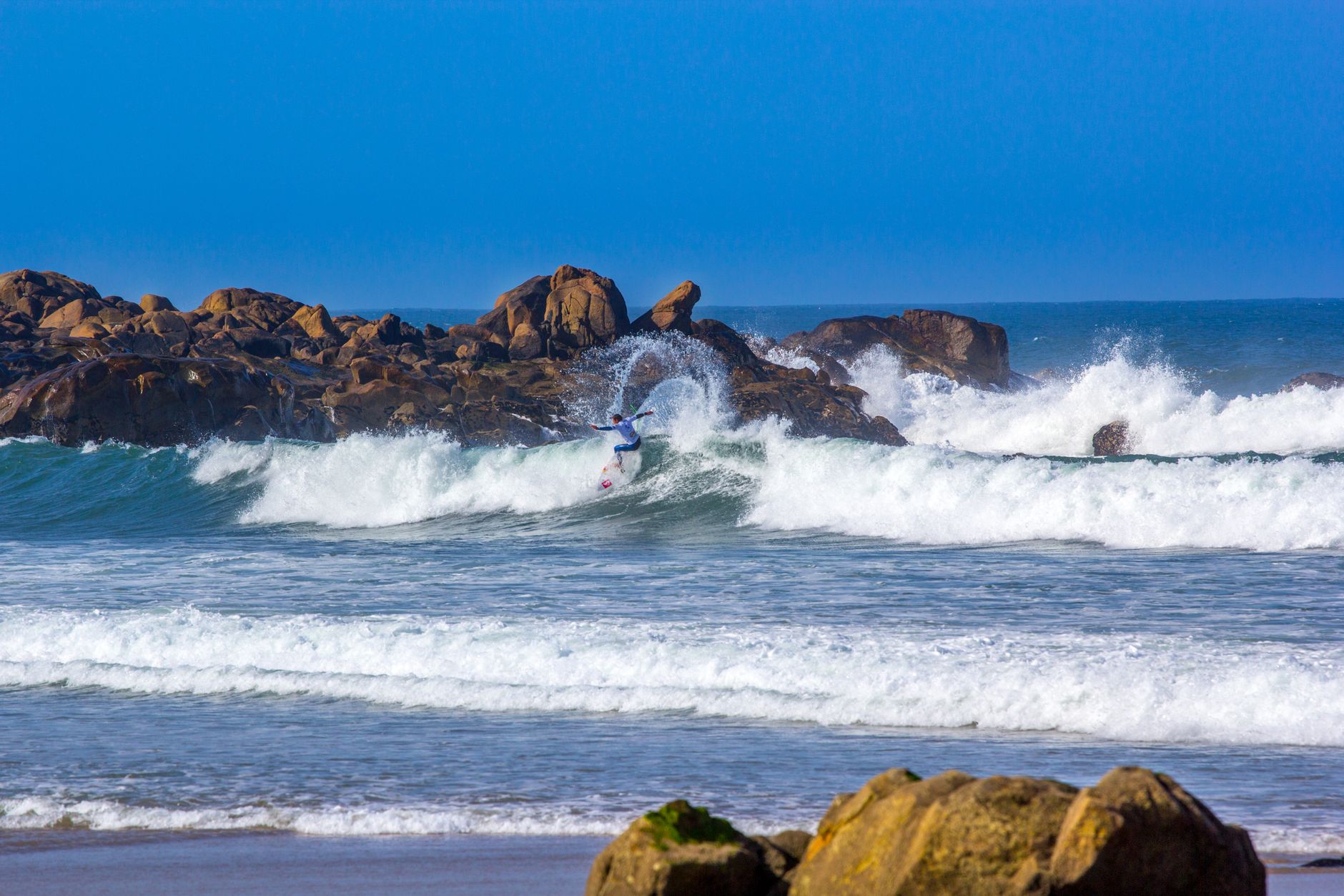 Surfer riding waves against rocky shore in Matosinhos, Porto, capturing the thrill of ocean sports.