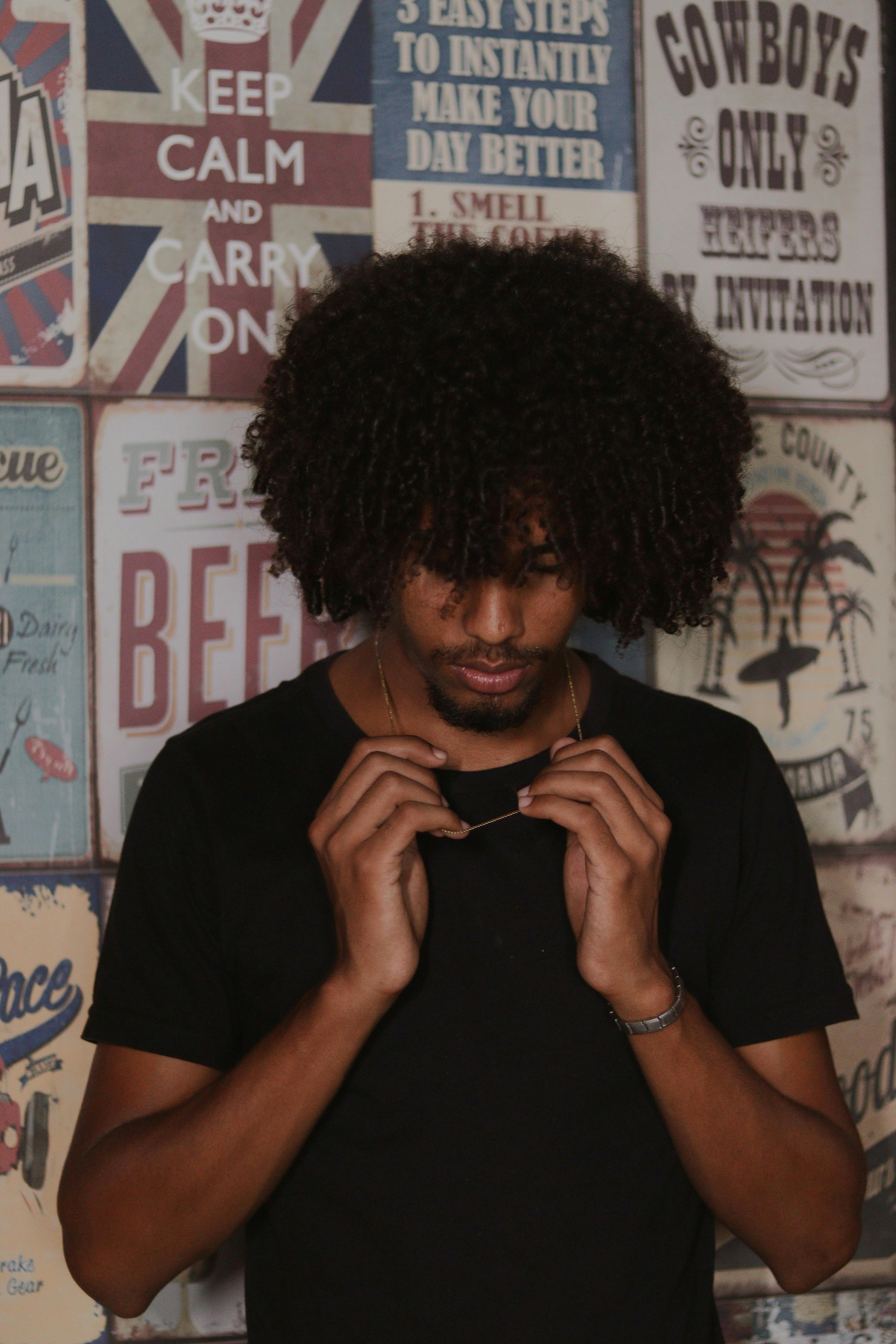 Portrait of a young man with curly hair in front of vintage posters wall.