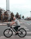 Man in White Shirt Riding Bicycle on Road