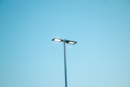 Modern street light against a clear blue sky, exemplifying minimalism and urban design.