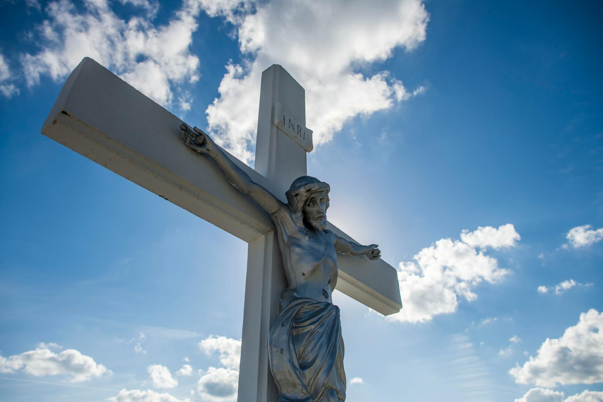 A striking sculpture of Jesus on the cross with a vivid blue sky background.