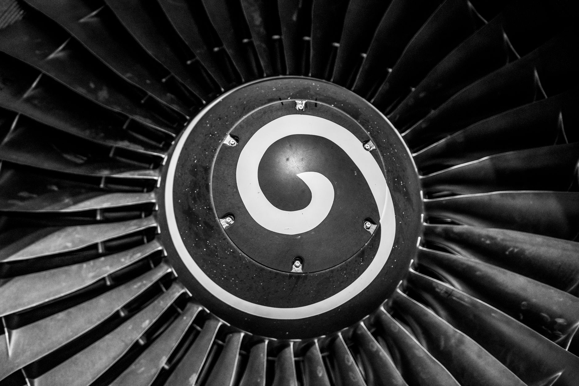 Detailed grayscale view of a jet engine turbine, showing the layered precision of its internal blades