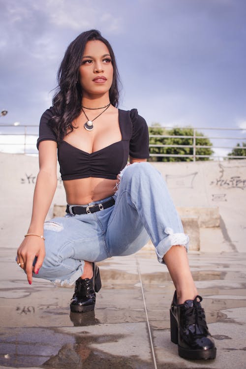 Woman in a Black Crop Top Crouching while Looking Away