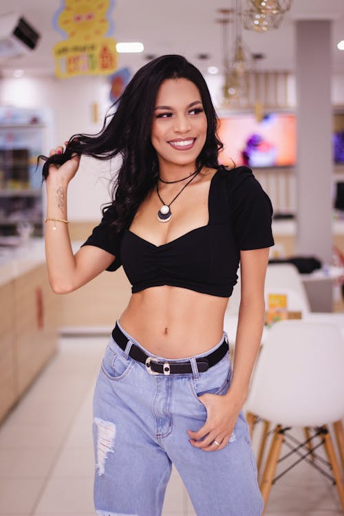 Woman in a Black Crop Top Touching Her Hair while Smiling