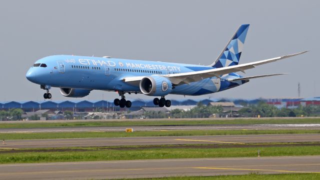 Etihad Airways aircraft with Manchester City branding landing on a runway, showcasing vivid livery. — lounges at Manchester Airport