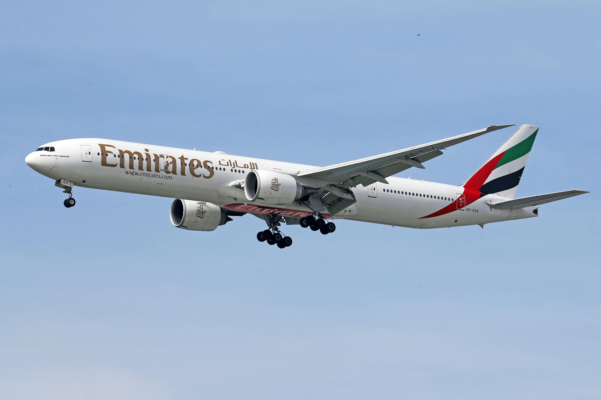 Emirates Boeing 777 aircraft mid-flight against a clear blue sky, showcasing modern air travel.