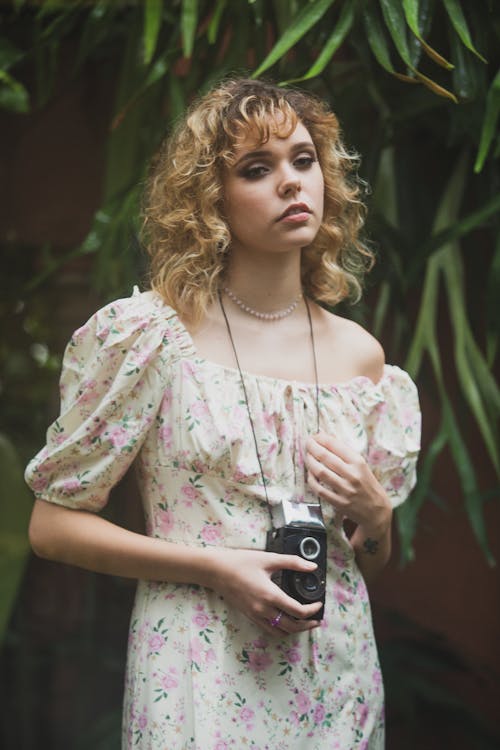 Woman in a Floral Dress with a Vintage Camera on her Neck 