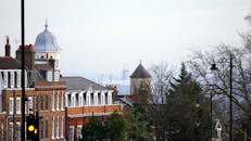 透过雾气，可以看到城市天际线中历史悠久的砖砌建筑和树木