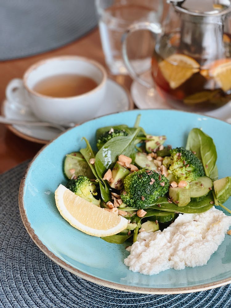 Vegetable Dish And Rice On Blue Ceramic Plate Beside Cup Of Tea