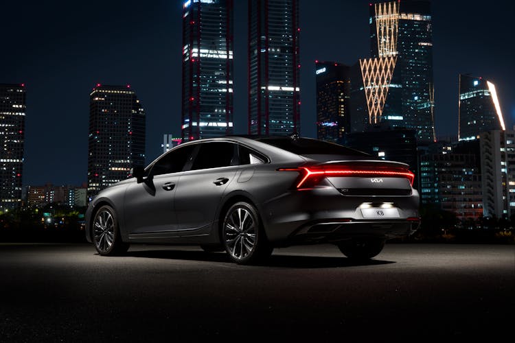 Black Modern Car Standing Illuminated And Big City In Background