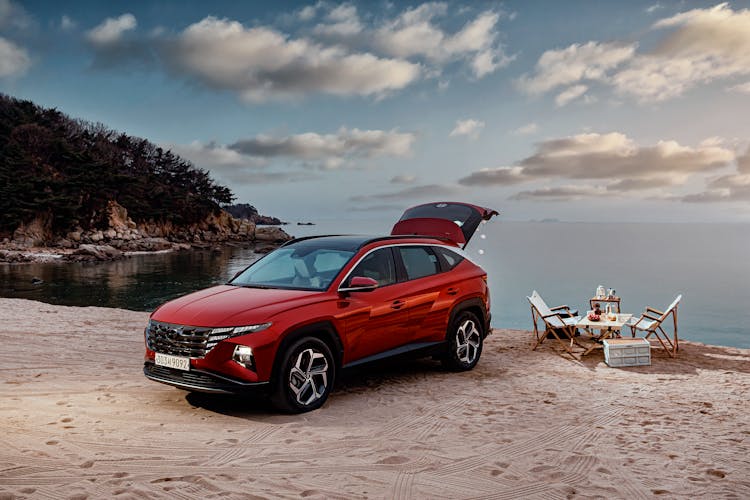 Red Car And A Table With Chairs On A Sandy Beach