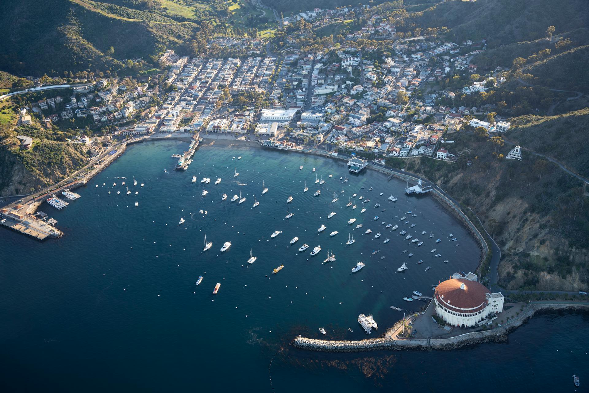 Stunning aerial view of Avalon Harbor on Catalina Island with boats and scenic coastline.
