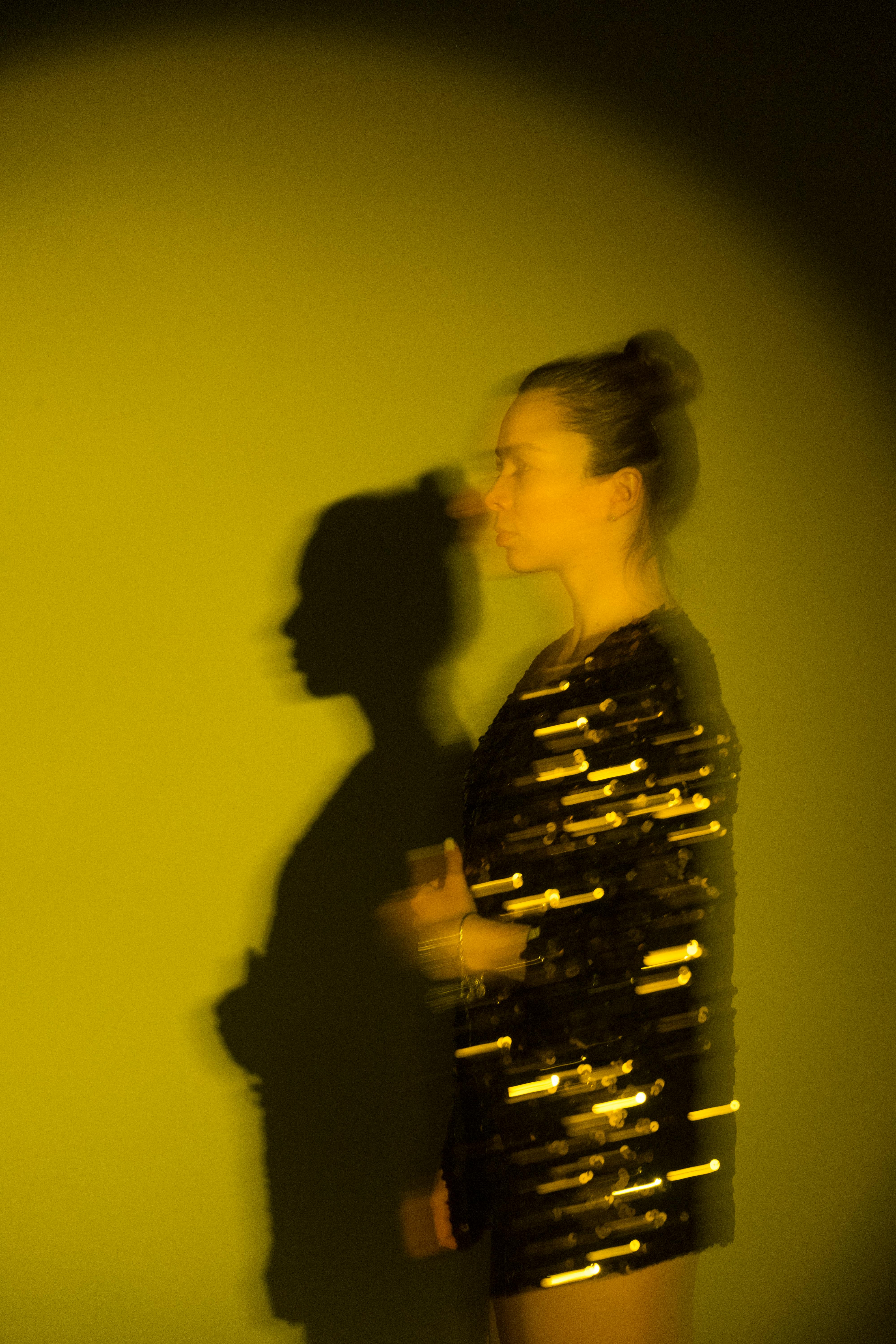 Blurred artistic portrait of a woman with a dramatic shadow against a yellow background.