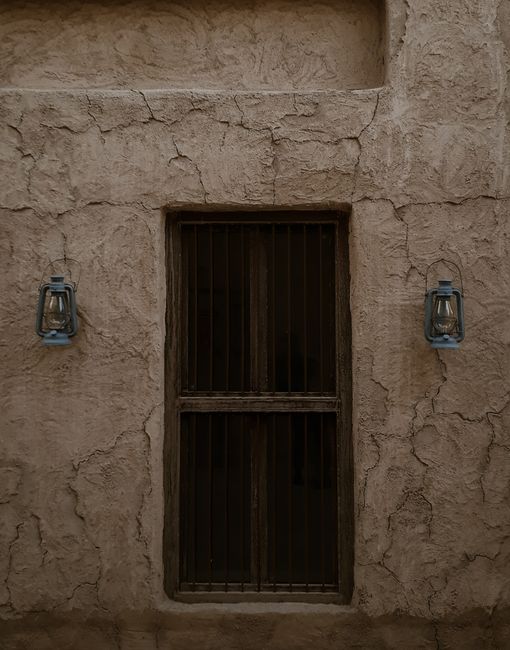 A rustic window with old lanterns on a textured wall in Dubai, UAE.