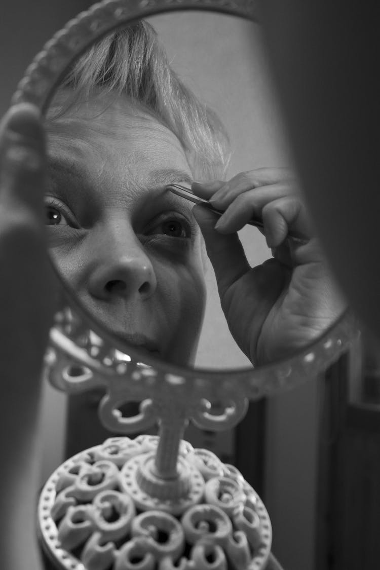 Grayscale Photo Of A Woman Plucking Her Eyebrow