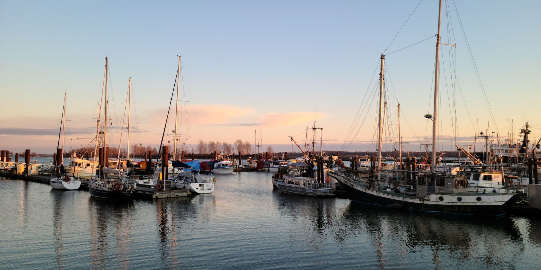 Explore a tranquil marina with boats and sailboats docked under a peaceful sunset sky in Richmond, BC, Canada.