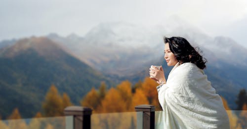 Woman Having a Coffee on a Balcony and Looking at the Mountains 