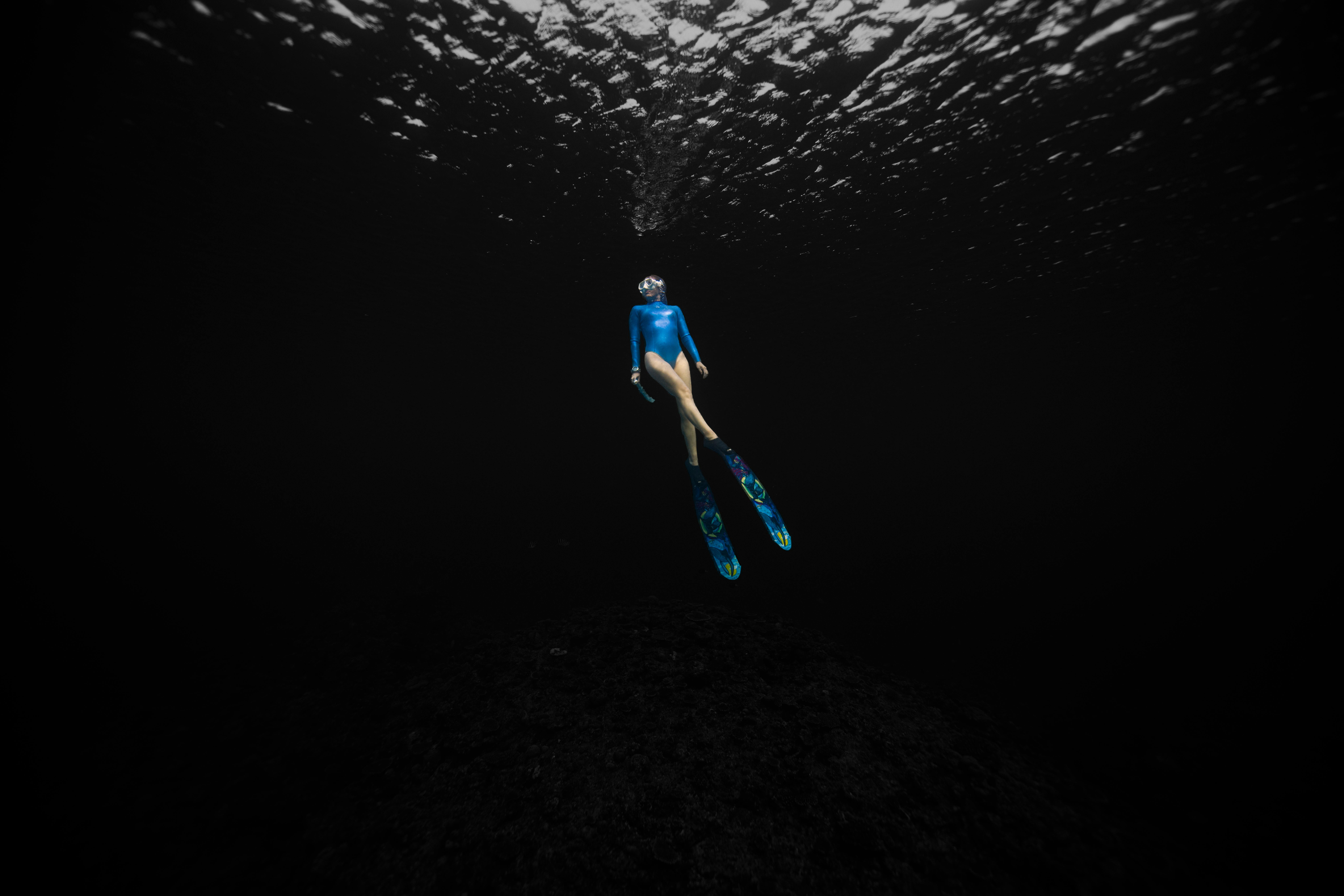 female free diver immersed in dark waters
