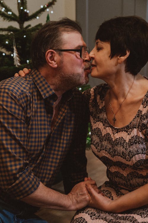 An Elderly Man Kissing a Woman while Holding Each Others Hand