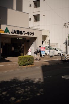 City street view with pedestrians near a parking entrance under bright daylight.