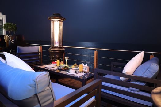 Romantic dinner setting on a balcony overlooking the sea at night, perfect for a cozy evening.