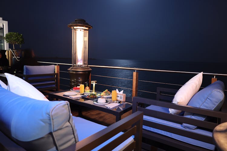 Table With Food On Balcony Near Body Of Water During Night Time