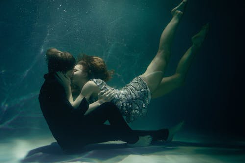 Couple embracing and kissing underwater in an artistic scene.
