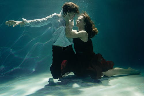 Photo of a Woman Holding a Man's Face Underwater