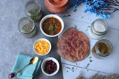 Top view of Indian dishes and spices featuring vibrant chutneys, breads, and herbs.