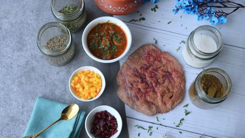 Top view of Indian dishes and spices featuring vibrant chutneys, breads, and herbs.