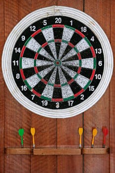 Close-up of a dartboard with colorful darts on a wooden background, ideal for sports themes.