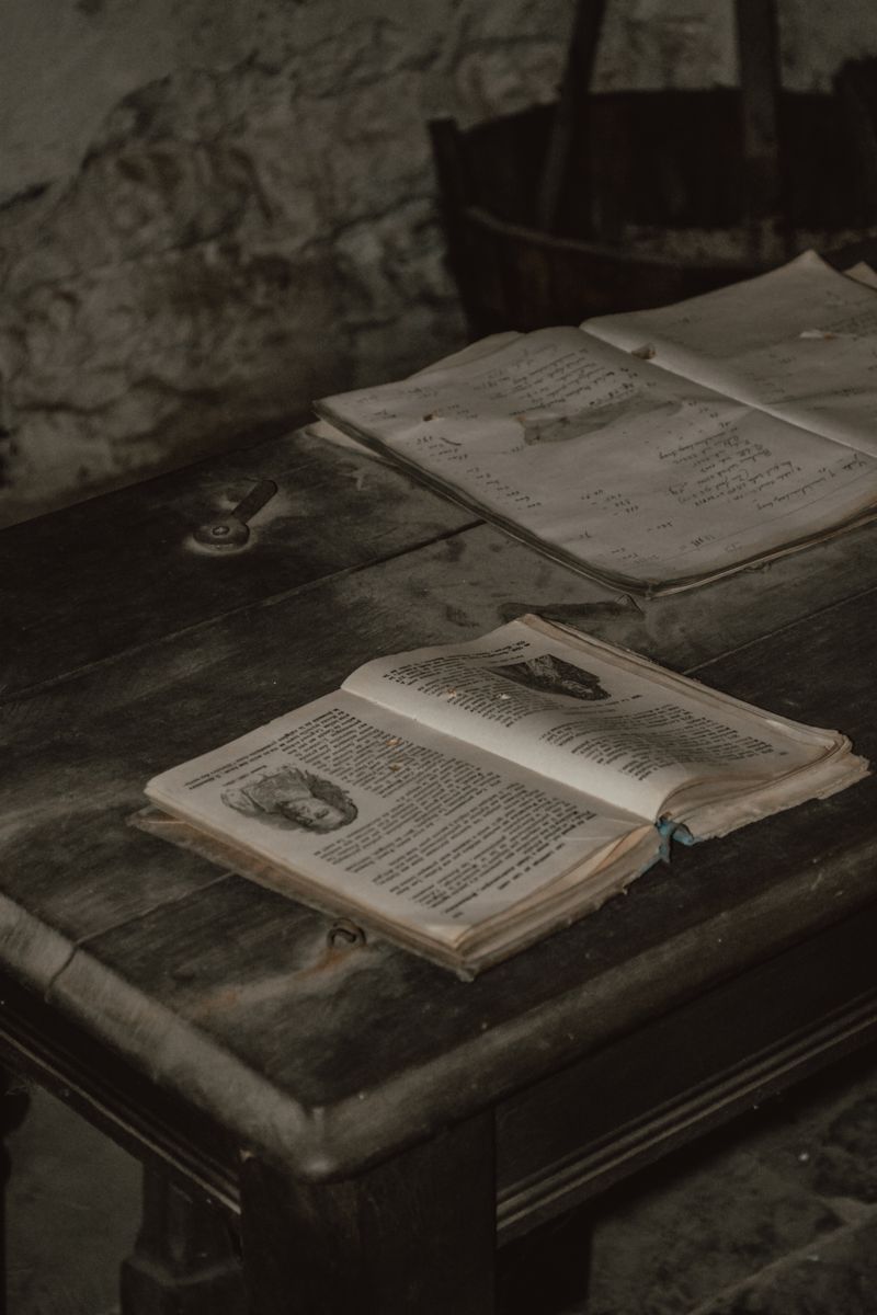 A pile of vintage open books on a rustic wooden table in a cozy indoor setting. A pile of vintage open books on a rustic wooden table in a cozy indoor setting.