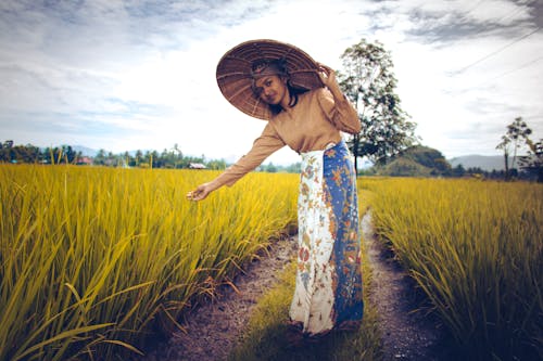 Mujer Vestida Con Top De Manga Larga Marrón Y Falda Blanca Y Azul Cerca De Plantas Verdes