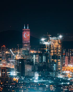 Stunning aerial view of Istanbul's skyline with illuminated skyscrapers and the Turkish flag at night.